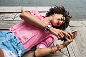 Young woman lying on bench with mobile phone