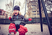 Cheerful girl swinging in playground