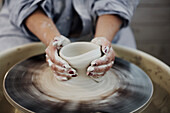Close up of woman making pot on potters wheel