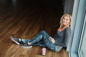 Portrait of woman sitting on wooden floor