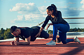 Woman kneeling next to man doing plank position