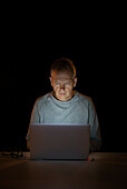 Mann mit Laptop in einem dunklen Raum