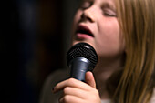 Mädchen hält Mikrofon und singt