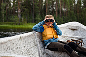 Boy on boat looking through binoculars
