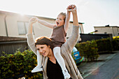 Mother carrying daughter on shoulders