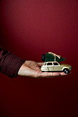 Hand holding toy car with Christmas tree on it