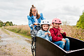 Mother pushing daughters in bicycle cart