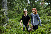 Mädchen und Junge tragen Korb im Wald