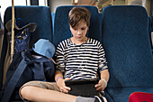 Boy using digital tablet in train