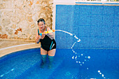 Woman with water pistol in swimming pool