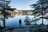 Mann schaut auf einen See im Winter