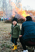Vater mit Sohn schaut auf ein Feuer im Park