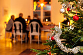 Decorated Christmas tree, people dining on background
