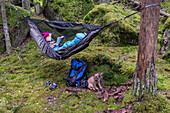 Woman reading book in hammock in forest