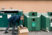 Mann wirft Müll in die Recycling-Tonne