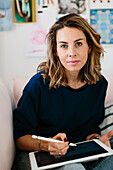 Woman sitting on sofa and using digital tablet