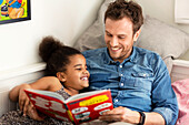 Father reading book to daughter