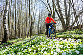 Woman cycling through spring forest