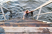 Frau schwimmt im See neben einer Holztreppe