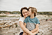 Mutter und Sohn küssen sich am Meer