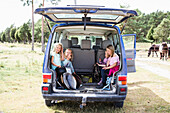 Children sitting in car trunk
