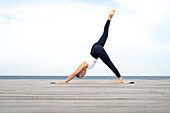 Woman practicing yoga on pier