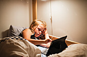 Mädchen benutzt digitales Tablet im Bett