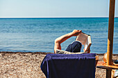 Mann liest ein Buch am Strand