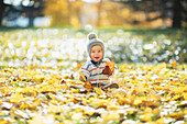 Baby playing with autumn leaves