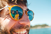 Women reflecting in mans sunglasses