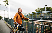 Man with bicycle standing on bridge
