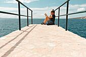 Frau liest ein Buch auf einem Bootssteg