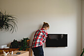 Frau hängt TV an die Wand