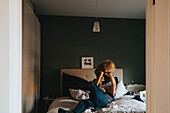 Boy playing with father on bed