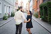 Smiling couple holding hands on street