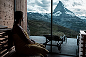 Frau schaut aus dem Fenster auf die Berge