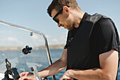 Mann telefoniert mit Handy auf einem Boot