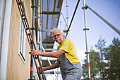 Älterer Mann steht auf einer Leiter