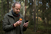 Mann mit Pilz und Mobiltelefon in der Hand