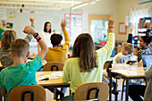 Children raising hands in classroom