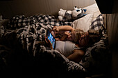 Mutter mit Tochter benutzt digitales Tablet im Bett