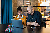 Coworkers using laptop in boardroom