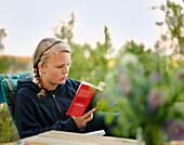 Mädchen im Teenageralter liest im Garten
