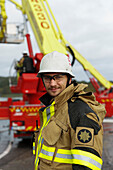 Portrait of young fire-fighter, fire engine on background