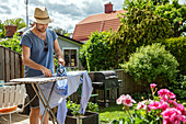 Mann bügelt Kleidung im Garten