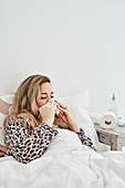 Ill woman in bed sneezing