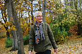 Ältere Frau geht im Herbst spazieren