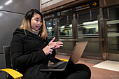 Woman at train station using laptop