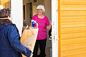Woman delivering shopping to senior woman