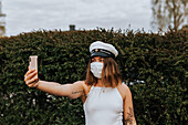 Frau mit Gesichtsmaske macht ein Selfie